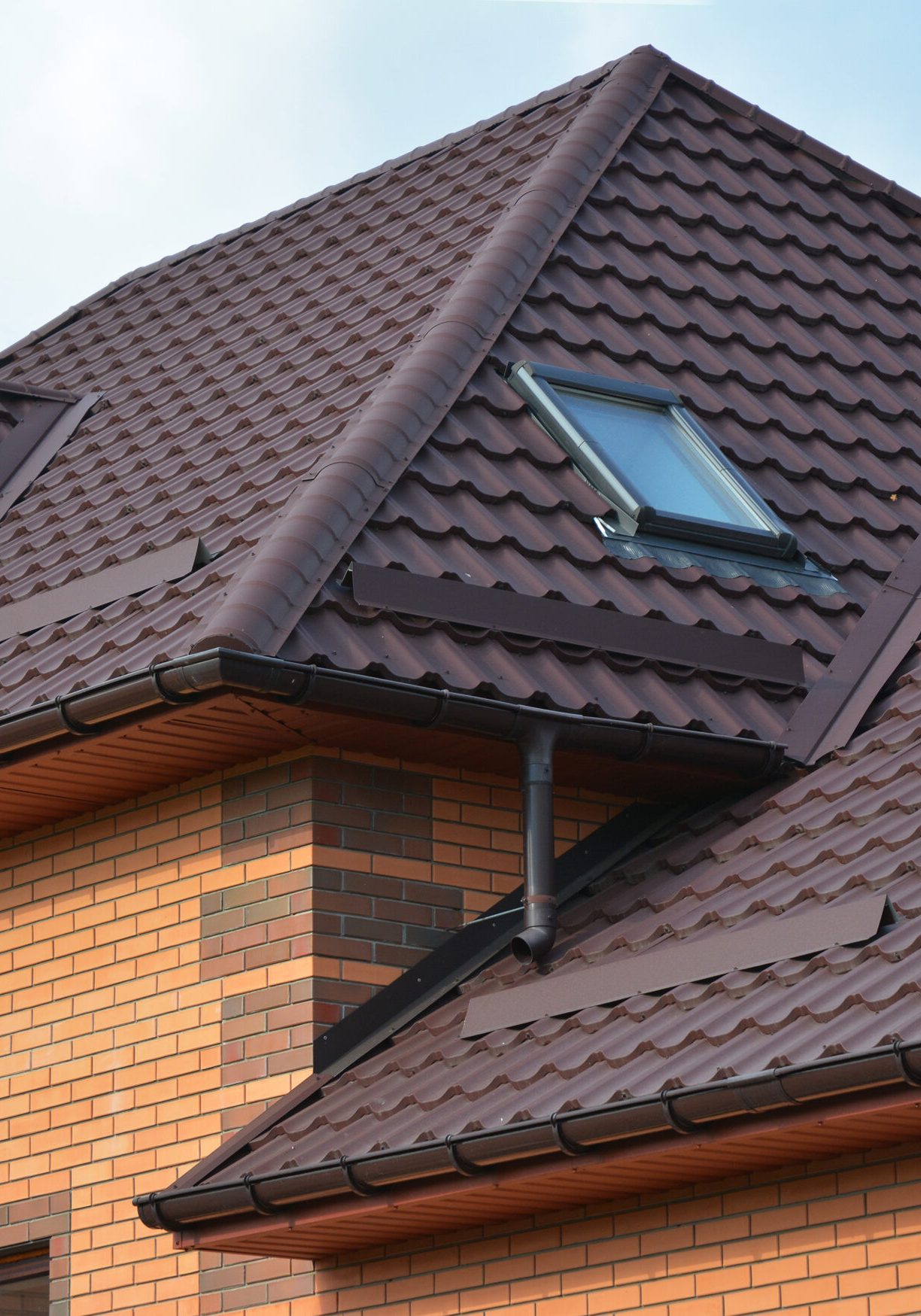 New roofing construction with attic skylights, rain gutter syste New roofing construction with attic skylights, rain gutter system, roof windows and roof protection from snow board, snow guard exterior. Modern House Construction. Hip and Valley roofing types.