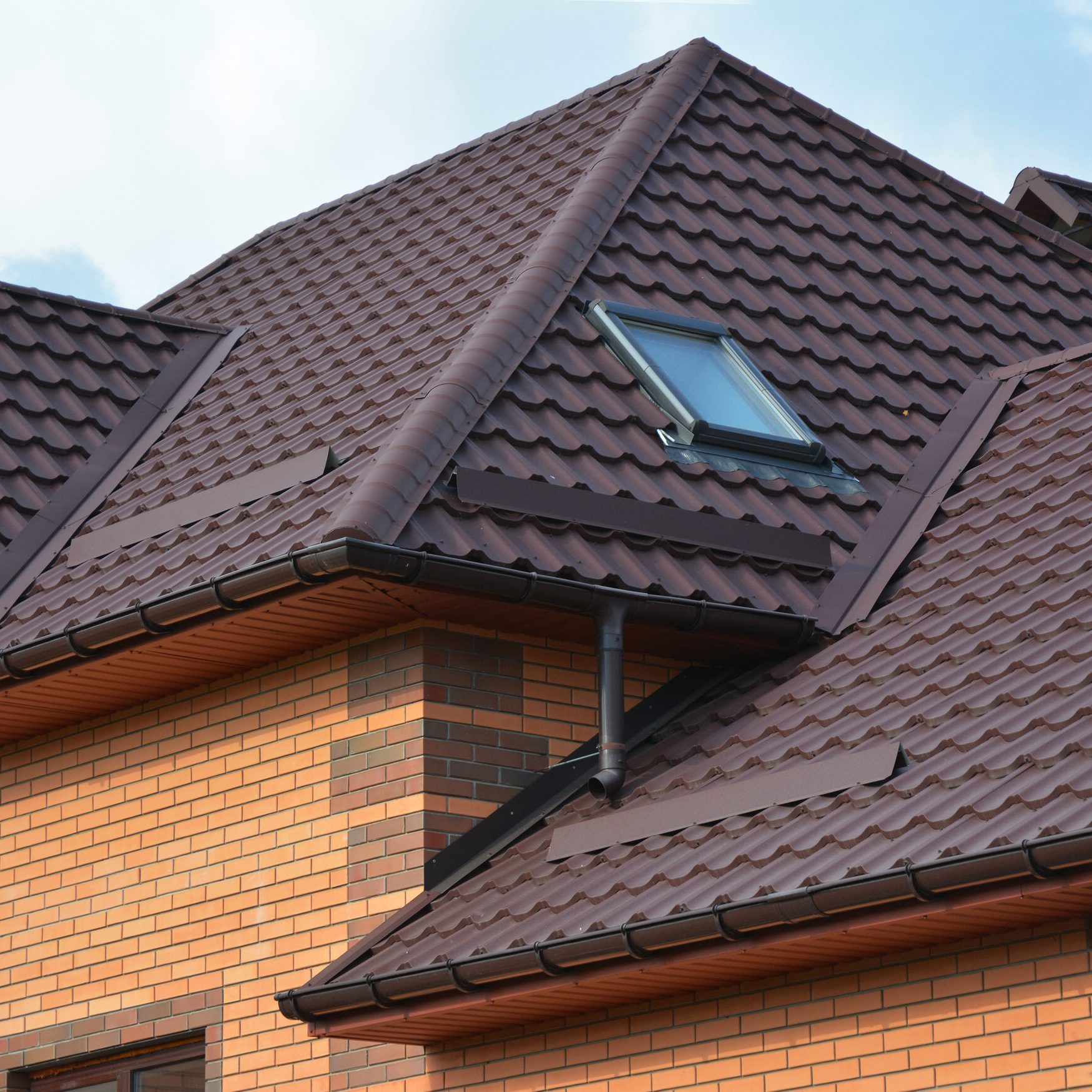 New roofing construction with attic skylights, rain gutter syste New roofing construction with attic skylights, rain gutter system, roof windows and roof protection from snow board, snow guard exterior. Modern House Construction. Hip and Valley roofing types.